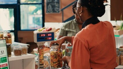 Local merchant weighting and scanning produce for customer at organic farmers market, african american women supporting healthy eating. Buyer shopping for chemicals free vegetables. Tripod shot.