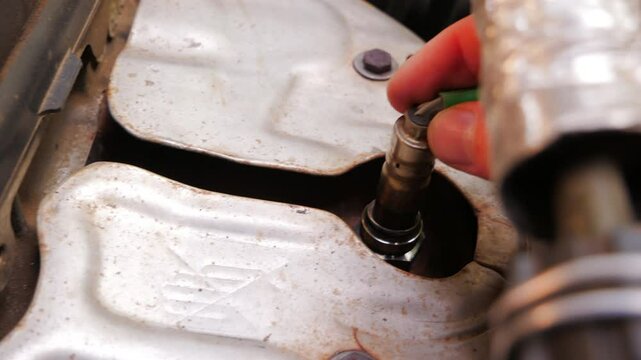 Close up view captures a mechanic's hand installing a new lambda sensor into a car engine, highlighting the precision and care involved in automotive repair and maintenance tasks