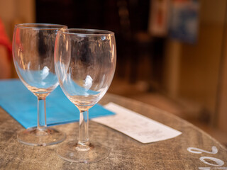 Two glasses, a menu and a receipt on an outside wooden restaurant table