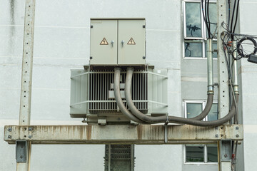A large eletric transformer is mounted on concrete beams and poles