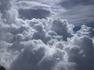 Puffy cumulus clouds seen outside an airplane window.