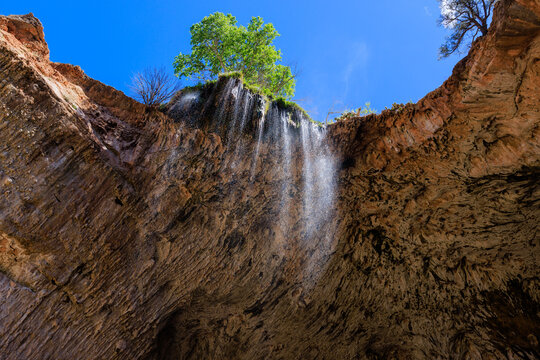 The view looking up as water cascades off of the travertine natural bridge at Tonto Natural Bridge State Park near Payson, Arizona.