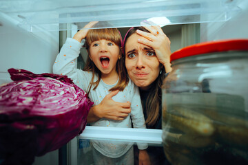 Mother and Daughter Feeling Hungry Looking in the Refrigerator. Mom and child having a negative...