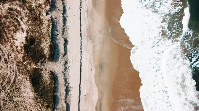 Vista a&eacute;rea de drone voando sobre uma bela praia com vista para as ondas do oceano e &aacute;gua batendo na praia de areia do &acirc;ngulo superior