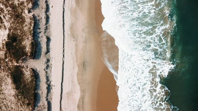 Vista a&eacute;rea de drone voando sobre uma bela praia com vista para as ondas do oceano e &aacute;gua batendo na praia de areia do &acirc;ngulo superior