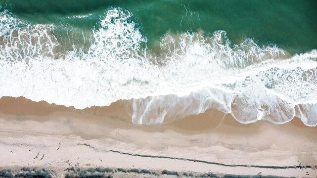 Vista a&eacute;rea de drone voando sobre uma bela praia com vista para as ondas do oceano e &aacute;gua batendo na praia de areia do &acirc;ngulo superior