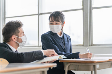 マスクで授業する外国人教師と生徒（感染対策）
