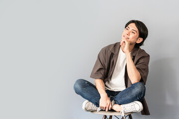 椅子に座るスニーカーとジーンズ姿のさわやかな男性
