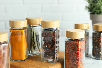 Different spices in glass jars on white marble table
