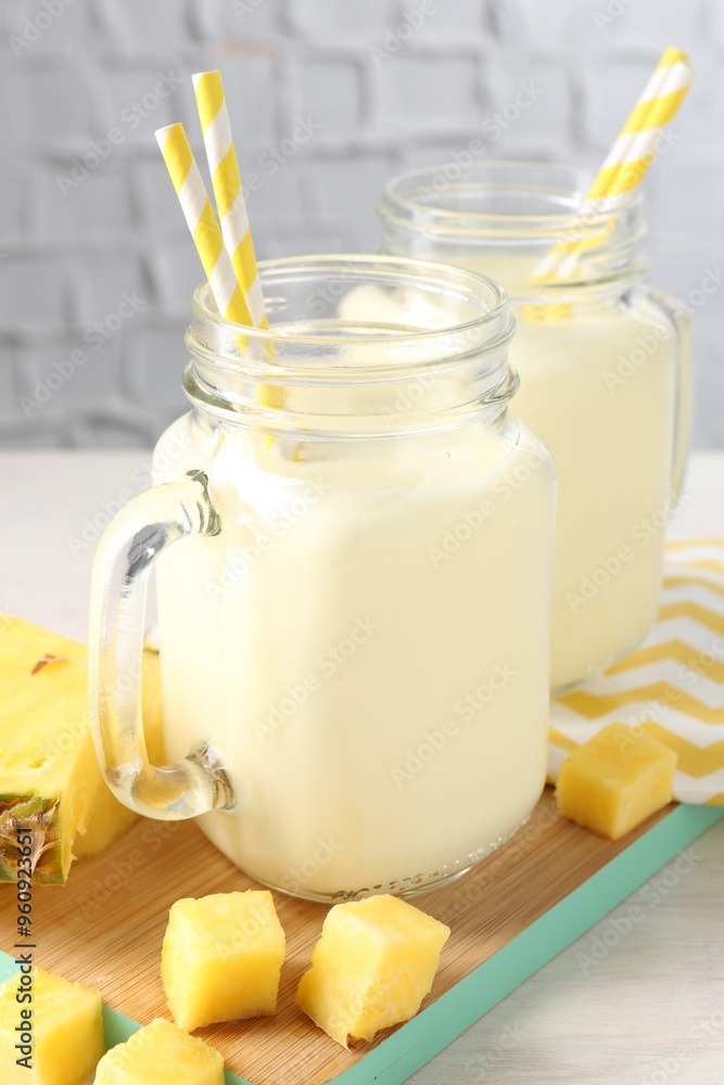 Sticker Tasty pineapple smoothie in mason jars and fresh fruit on table