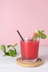 Tasty watermelon drink in glass and mint on white wooden table