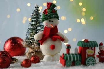 Cute decorative snowman and other Christmas decor on artificial snow