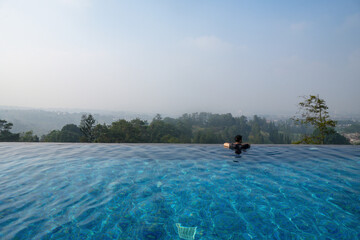 Man enjoying the infinity pool with a scenic view. Summer vacation at poolside.