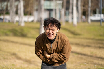 Young latin man falling about laughing