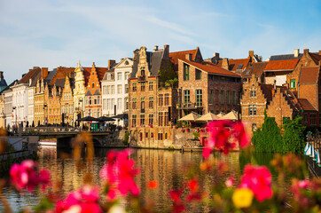 Obraz premium View of picturesque blooming area with typical residential buildings in historic center of Ghent city along Leie river on summer day, Belgium