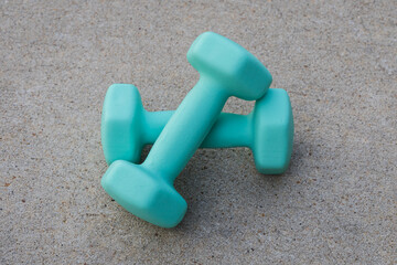 Two turquoise dumbbells on concrete background