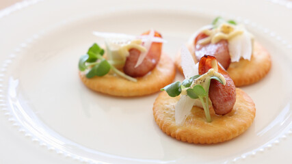 Canapé party appetizer with sausage and cream cheese on crackers