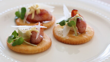 Cream cheese and sausage cracker canapés prepared as party appetizers