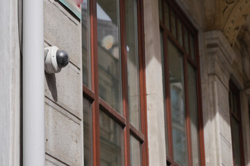 A surveillance camera has been installed on the exterior of the building featuring reflections