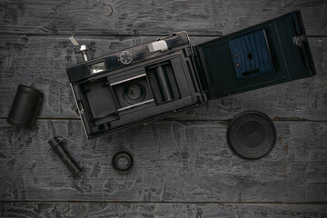 Vintage Film Camera on Wooden Background with Film Roll and Lens Cap