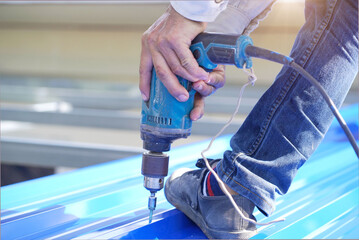 Construction worker install new roof,Roofing tools,Electric drill used on new roofs with Metal Sheet.    