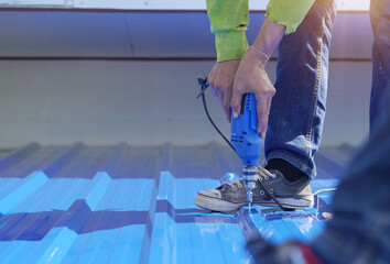 Construction worker install new roof,Roofing tools,Electric drill used on new roofs with Metal Sheet.    