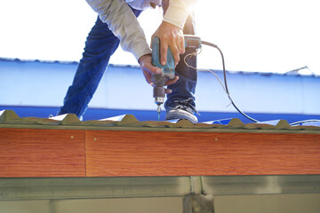 Construction worker install new roof,Roofing tools,Electric drill used on new roofs with Metal Sheet.    