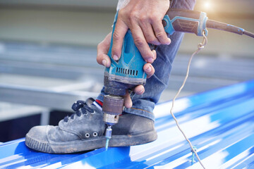 Construction worker install new roof,Roofing tools,Electric drill used on new roofs with Metal Sheet.    