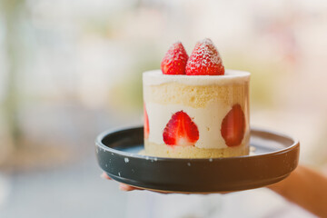 A woman's hand is holding a strawberry shortcake.