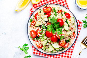 Bulgur salad with tomatoes, cucumbers and parsley.. White background, top view