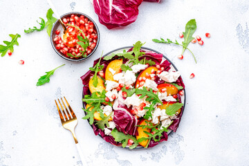 Italian salad with arugula, radicchio, peaches, ricotta cheese and pomegranate seeds on white...
