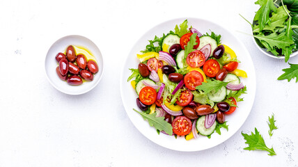 Vegan vegetable salad with olives, tomato, paprika, cucumber and onion, healthy mediterranean food. White background, top view