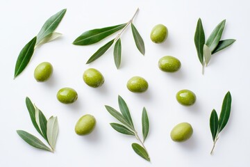 A flat lay of green olives and olive leaves on a white background.
