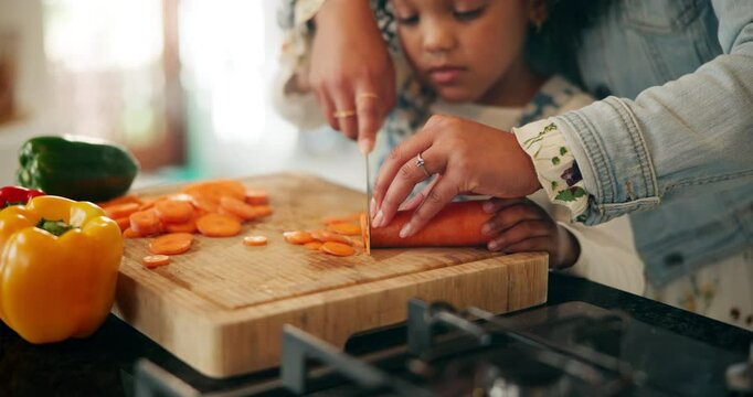 Hands, child and mother cutting vegetables for food, learning or cooking healthy lunch in home kitchen. Kid, parent and chopping board with knife closeup for carrots, organic meal and teaching girl