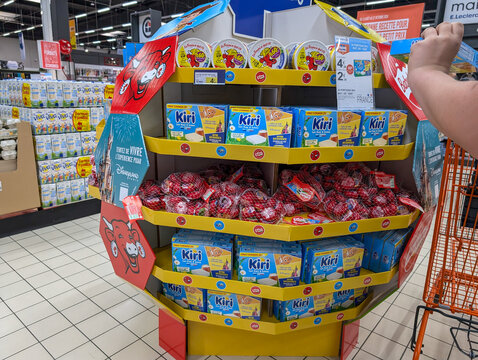 France, 26 August 2024: Display of Kiri cheese products in a supermarket with a customer reaching for an item.