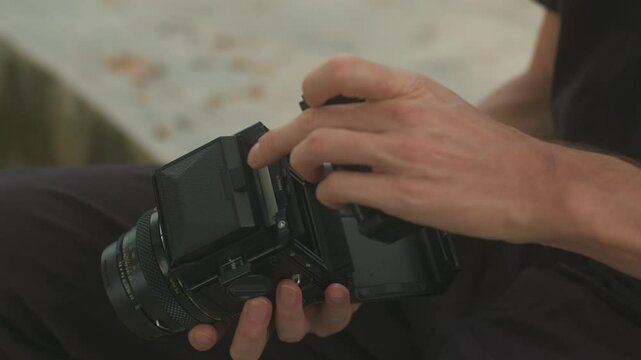 Setting up a film camera with a roll of film in hand to capture stunning moments creatively