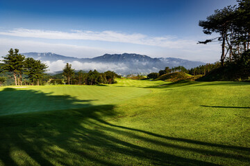 구름이 산중턱에 걸려있는 풍경이 보이는 산위의 골프장.