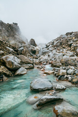 Columns of steam from hot springs rise into the sky above the mountain slopes.