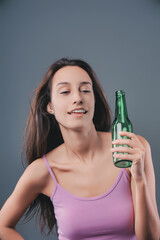 Tipsy woman smiles while holding green bottle.