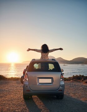 Mujer con los brazos abiertos en un acantilado viendo el atardecer al lado de un coche gris, de viaje, feliz, explorar, aventurera
