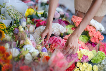 A woman is picking out flowers at a flower market