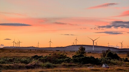 Wind turbines on wind farm under beautiful orange sunset sky at Galway, Ireland, green energy,...