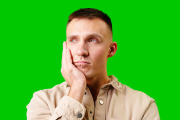 Young Man in Casual Attire Posing Thoughtfully Against a Bright Green Background