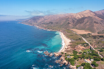 Fototapeta premium Beautiful landscape of Pacific Ocean coast along Highway 1 and Big Sur, aerial view, sunset, sunrise, fog. Concept, travel, vacation, weekend