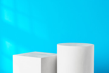 White geometric shapes on a clean surface against a bright blue background with soft shadows