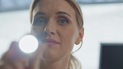 Closeup doctor using flashlight in clinic. Patient pov of medical examination