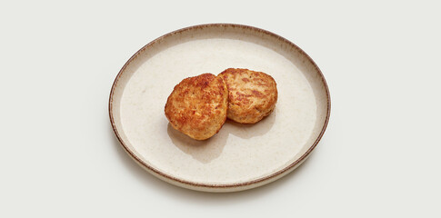 Two golden-brown, crispy chicken cutlets are artfully arranged on a beige plate against a clean white background.