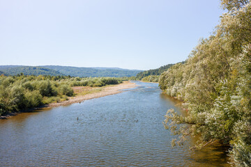 A winding river with a rocky shore and lush vegetation in the mountains