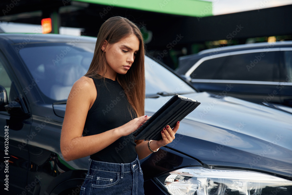 Wall mural digital tablet in hands. woman is near her car outdoors