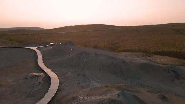 Drone shot flying around a mud volcano at the Mud Volcanoes Tourism Complex in the Qobustan National Park in Azerbaijan at sunset.